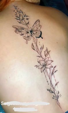 the back of a woman's stomach with flowers and butterflies tattoo on her left side