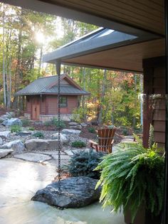 the back porch has a swing set and rock garden area, along with a small cabin in the background