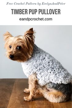 a small dog sitting on top of a wooden table wearing a gray and white sweater