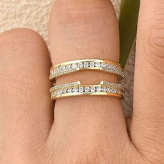 a woman's hand with two gold rings on it and one diamond ring in the middle