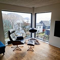 a living room with two chairs and a flat screen tv on the wall in front of large windows