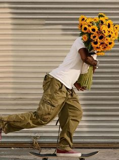 a man riding a skateboard down a street holding flowers on top of his head