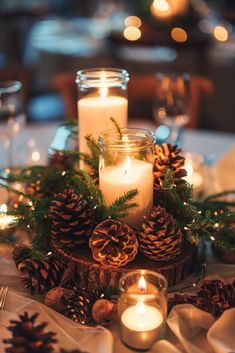 candles are lit on a table with pine cones