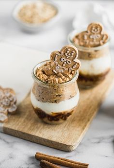 two small jars with cookies in them on a cutting board next to cinnamon sticks and spices