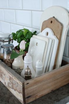 a wooden tray filled with dishes and utensils on top of a kitchen counter