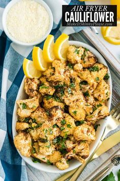 a white bowl filled with cauliflower next to lemon wedges and parsley