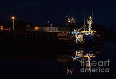 a boat is docked at the dock in the dark by some lights on it's side