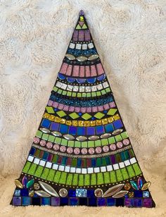 a colorful stained glass christmas tree sitting on top of a white furnishing wall