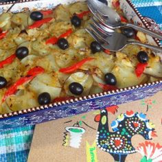 a casserole dish with olives, onions and peppers on a colorful table cloth