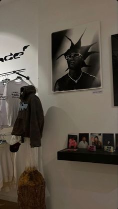 a clothing store display with clothes hanging on the wall and pictures on the wall behind it