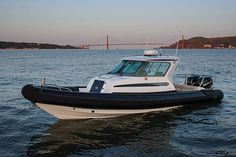 a black and white boat floating on top of the ocean next to a large bridge