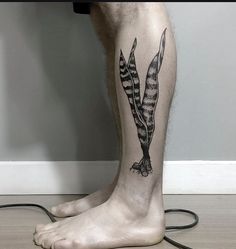 a man with a tattoo on his leg that has two feathers attached to the legs