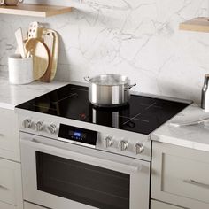 a stove top oven sitting inside of a kitchen next to white cupboards and counter tops