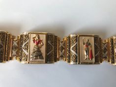 "Gorgeous gold gilt and mother of pearl in-laid Spanish toledo damascene five link bracelet featuring a lady dressed in a flamenco dress and a bull fighter in alternate panels. The bracelet has a push in slide closure and also comes with a safety chain. According to Wikipeda \"Damascening is the art of inlaying different metals into one another--typically, gold or silver into a darkly oxidized steel background--to produce intricate patterns similar to niello\". Approximate measurements: Bracelet Traditional Enamel Jewelry Collectible, Vintage Yellow Gold Festive Jewelry, Festive Ornate Bracelets, Festive Vintage Yellow Gold Jewelry, Collectible Yellow Gold Bracelets, Enamel Bracelet Jewelry For Wedding, Formal Engraved Jewelry For Festivals, Elegant Festive Enamel Jewelry, Vintage Bracelets For Festivals