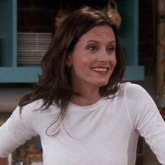 a woman standing in front of a table with food on it and smiling at the camera