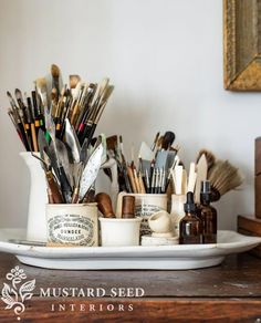 there are many different types of paint and brushes in the cup on the table next to each other