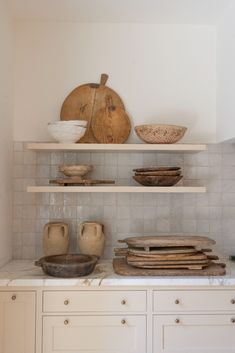 the shelves in the kitchen are filled with bowls, plates and other things on them