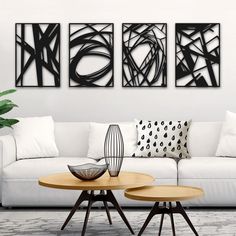 three black and white art pieces on the wall above a couch in a living room