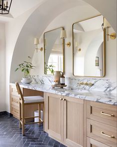 a bathroom with marble counter tops and two mirrors on the wall, along with wooden cabinets