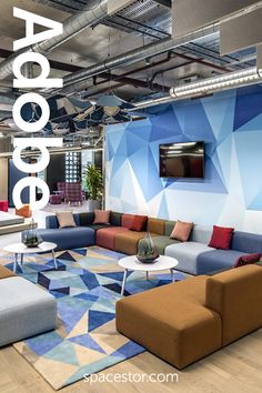 an office lobby with blue and brown couches, coffee table and television on the wall