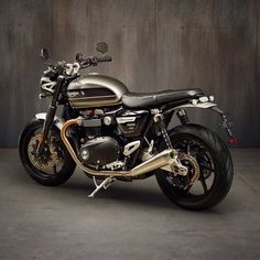 a motorcycle is parked in front of a gray wall and black leather seat on it's back end