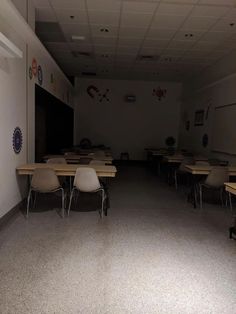 an empty classroom with desks and chairs in the middle, on carpeted floor