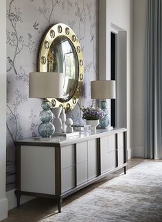 a living room with a large mirror on the wall next to a dresser and lamps