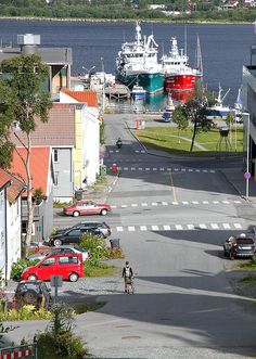 a person riding a bike down a street next to some houses and boats in the water