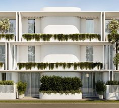 an apartment building with white balconies and plants growing on the side of it