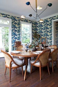 a dining room table and chairs with blue wallpaper on the walls in front of them