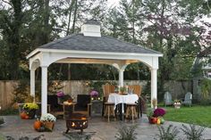 a gazebo sitting in the middle of a yard with tables and chairs around it