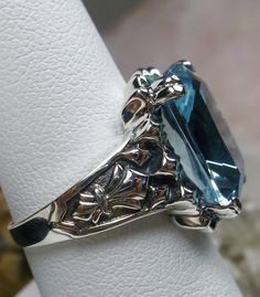 <> #144 {Made To Order} Inspired by Gothic designs, I now offer this lovely filigree inspiration in sterling silver. This is a flawless Man-made/simulated aquamarine is 15mm (5/8th of an inch) by 12mm (1/2 inch) in size. The inside of the band is etched 925. Notice the intricate and detailed Victorian design of the antique patina silver filigree setting all the way down the band. This is an exquisite rendition of an antique filigree ring.... and is ready to wear. A gift-box is included for Victorian Hallmarked Blue Topaz Jewelry, Victorian Blue Topaz Hallmarked Jewelry, Victorian Style Hallmarked Blue Topaz Jewelry, Heirloom Blue Topaz Diamond Cut Jewelry, Anniversary Jewelry With Engraved Blue Topaz, Antique Blue Round Cut Jewelry, Victorian Blue Topaz Jewelry For Anniversary, Victorian 14k White Gold Jewelry Gift, Victorian 14k White Gold Jewelry As Gift