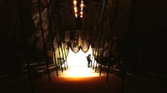 a person is standing in the middle of a dark hallway with flags hanging from it