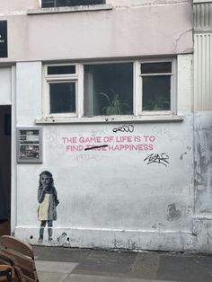 a painting on the side of a building that says the game of life is to find happiness