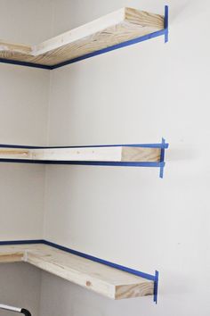 two shelves with blue tape on them in the corner of a room, one is empty