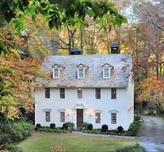 a large white house with two windows in the front and one on top of it's roof