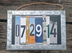 the license plates are hanging from a rope on a wooden fence, which is decorated with metal strips and numbers