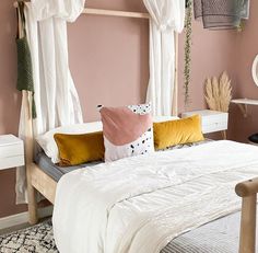 a bedroom with pink walls, white curtains and a bed in the middle is decorated with various colored pillows