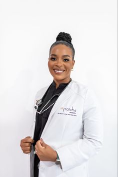 a woman in a white lab coat and black tie smiling at the camera with her hands on her hips