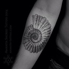 a black and white photo of a tattoo on someone's arm with an image of a shell