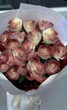 a bouquet of pink and white roses sitting on top of a table