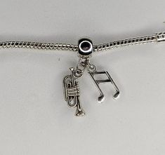 a silver bracelet with musical notes and a trumpet charm on it's clasps