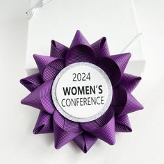 a purple bow with the words women's conference written on it is displayed in front of a white background