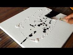 someone is painting on a canvas with black and white paint