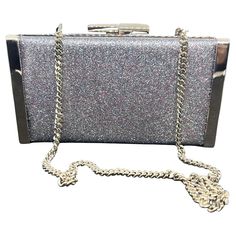 This Jimmy Choo ballet silver is crafted from fine glitter fabric and radiates elegance and sophistication. The sleek rectangular shape is enhanced by a shimmering silver glitter exterior that sparkles under the light, creating a mesmerizing effect. The subtle multicolor glints within the fine glitter add depth and dimension, while the silver-tone metal trim along the edges provides a polished finish, reflecting the luxury synonymous with the Jimmy Choo brand. The clutch features a secure metal Metal Bag, Red Louboutin, Jimmy Choo Heels, Blue Sunglasses, Metallic Bag, Metal Trim, Glitter Fabric, Jimmy Choo Shoes, Minimalist Aesthetic