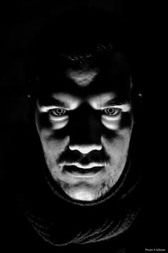 black and white photograph of a man's face with his eyes glowing in the dark