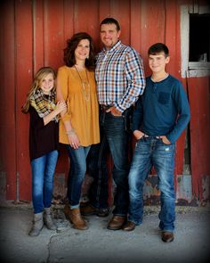 a family poses in front of a red barn