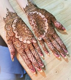 two hands with henna tattoos on them sitting on a wooden table next to each other