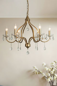 a chandelier hanging from the ceiling in a room with flowers and vases