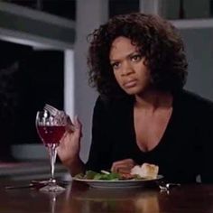 a woman sitting at a table with a plate of food and a glass of wine